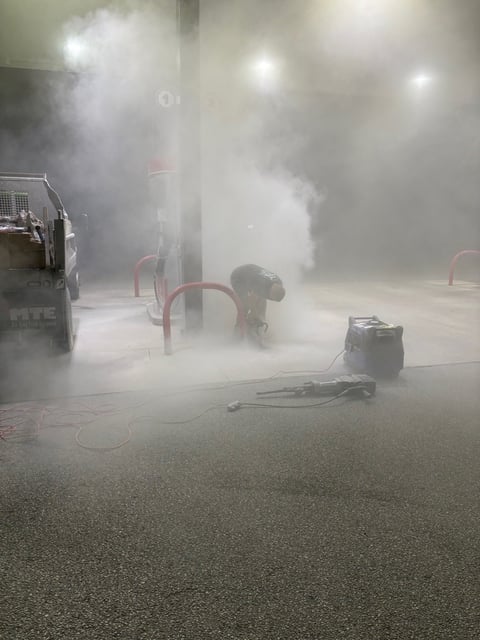 Dry cleaning machine spraying steam and cleaning solution onto parking garage floor during maintenance procedure