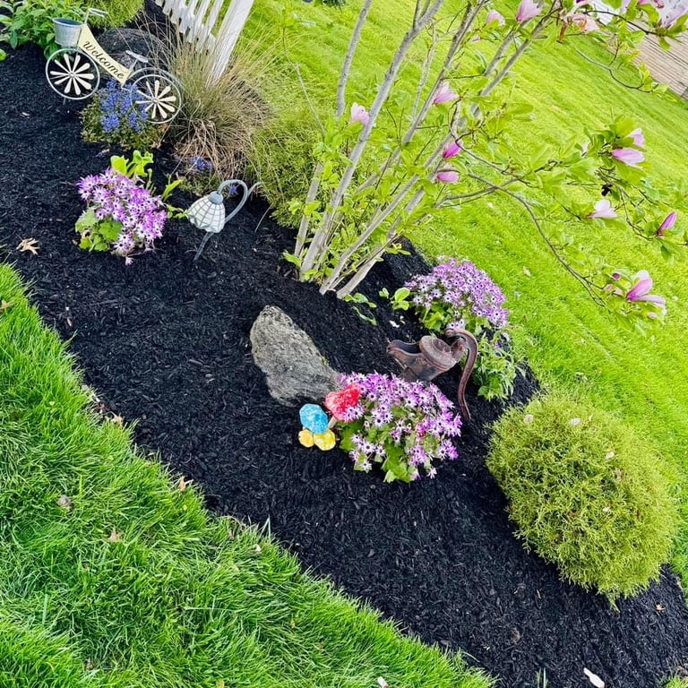 Garden bed with black mulch, colorful flowers and decorative stones