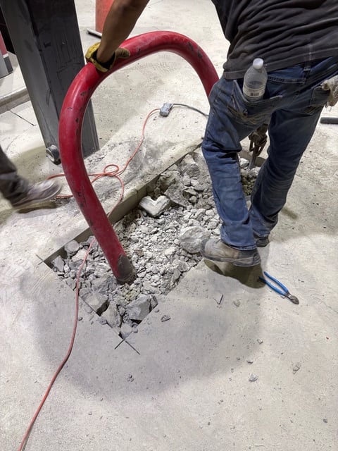 Worker using a red pneumatic jackhammer to break up concrete during construction work
